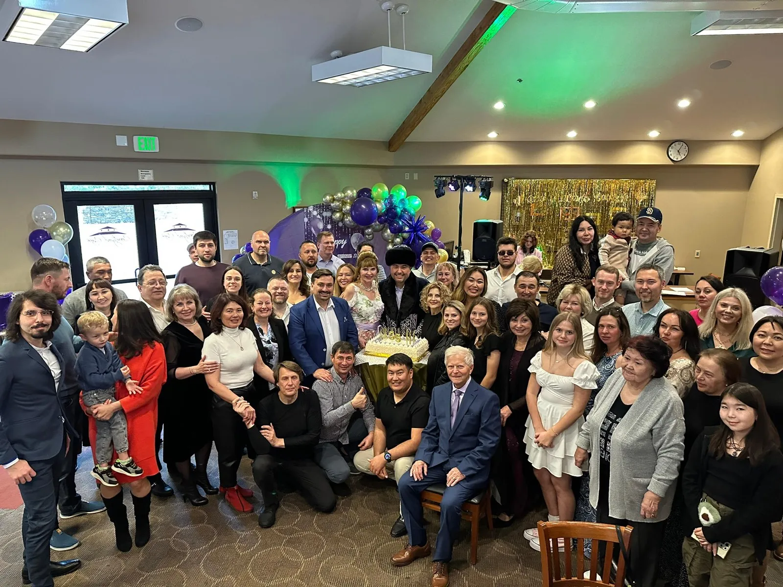 Family and friends gathered for Maxim's 55th birthday by the balloon arch and cake