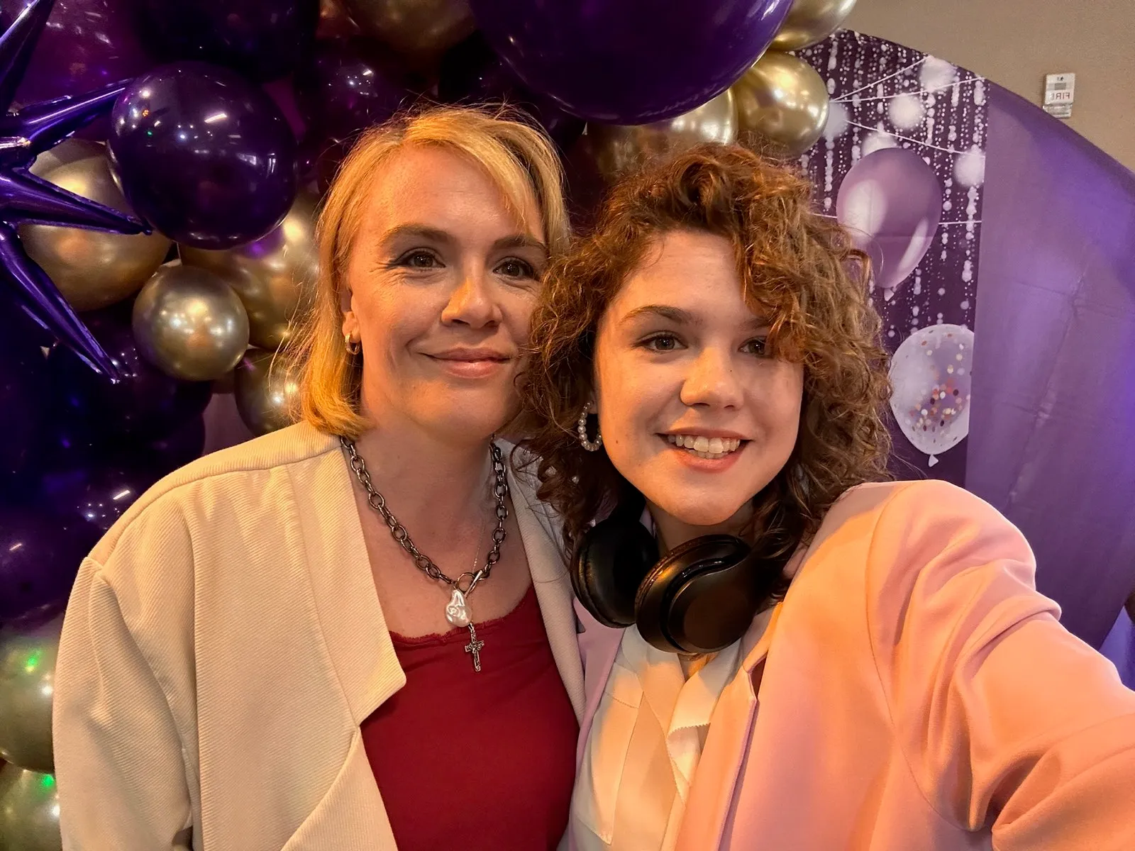 Host and DJ by the purple-and-gold 55 balloon wall at a birthday party