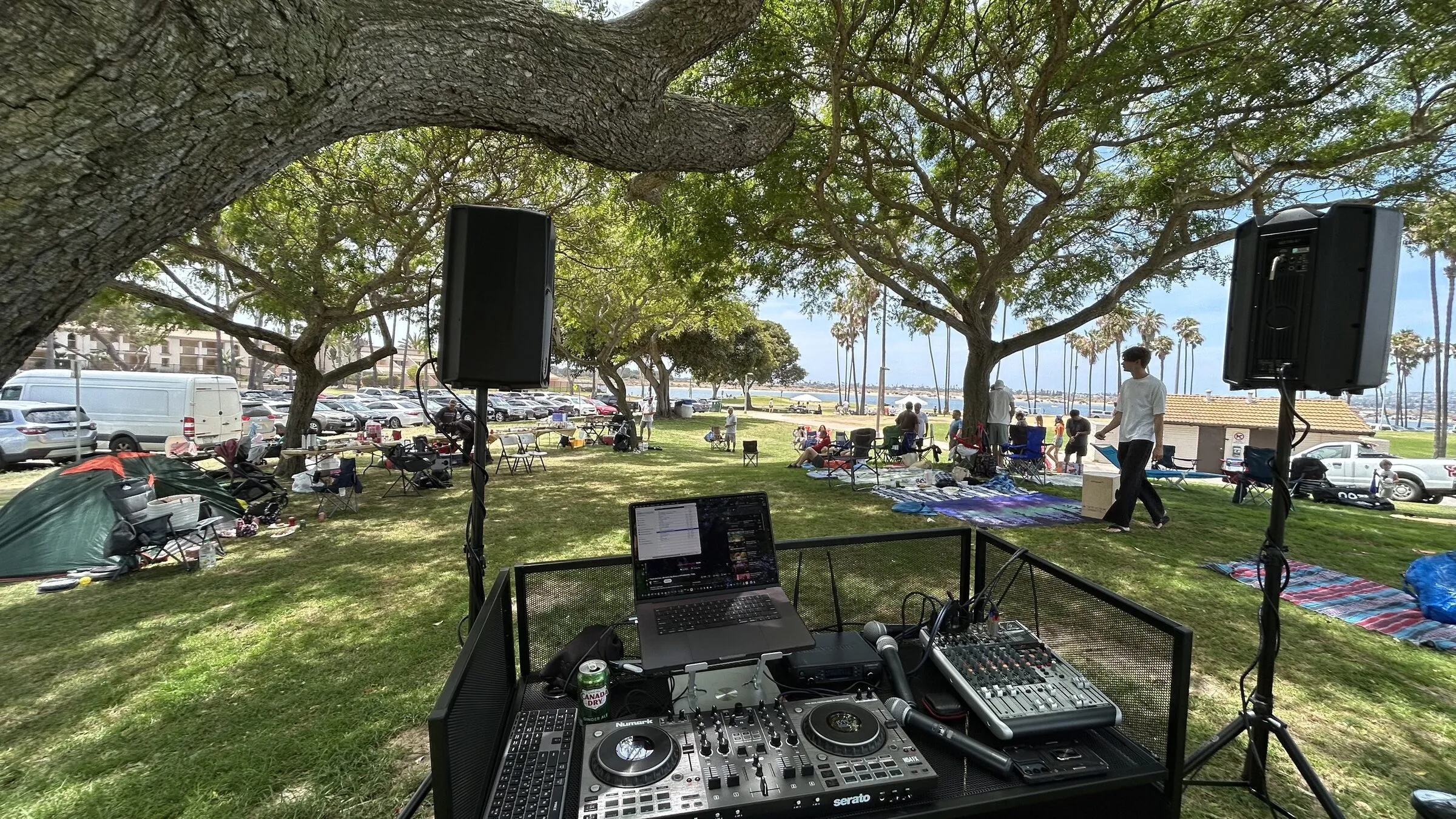 DJ booth, mixer and PA speakers set up on the grass at an outdoor party by Mission Bay, San Diego