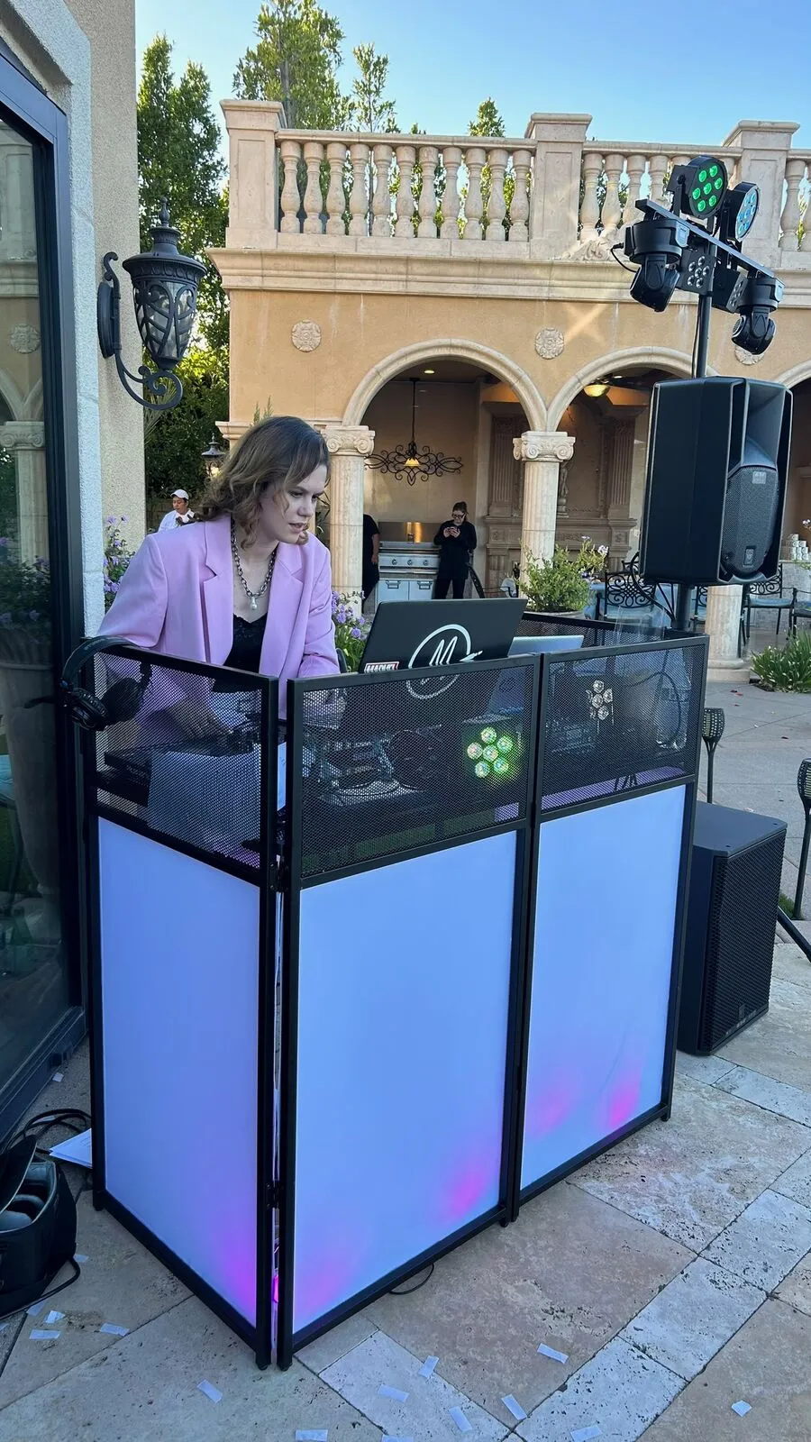 Lit DJ booth, speakers and a lighting rig in front of the arched terrace at a Poway estate wedding